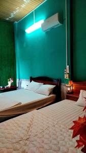 2 camas en un dormitorio con una pared verde en Let's go CAN THO - CAN THO FARMSTAY, en Ấp Phú Thạnh (4)