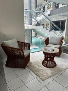 uma sala de estar com duas cadeiras e uma mesa e uma piscina em Nautillus Hotel na Parnaíba