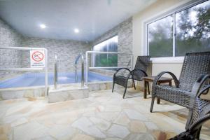 um quarto com uma piscina com cadeiras e uma mesa em VELINN Pousada Highland em Santo Antônio do Pinhal