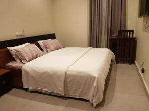 una camera da letto con un grande letto con lenzuola bianche e cuscini rosa di Krotia Lodge Atimpoku 