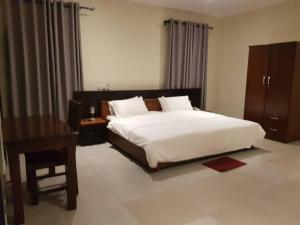 una camera con un grande letto bianco e una scrivania di Krotia Lodge Atimpoku 