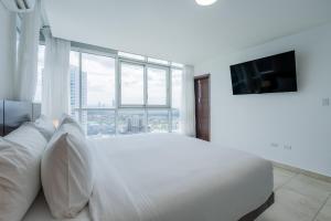 a white bedroom with a large bed and a large window at Fantastic 2BR with balcony in Costa del Este in Panama City