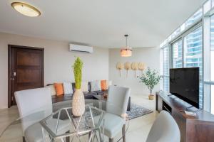a dining room with a glass table and white chairs at Fantastic 2BR with balcony in Costa del Este in Panama City