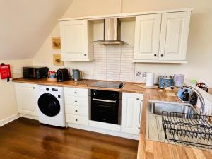 cocina con armarios blancos, fregadero y lavavajillas en Top floor double en-suite BR apartment central Matlock, en Matlock