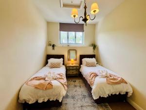 two beds in a small room with a mirror at Top floor double en-suite BR apartment central Matlock in Matlock +13 photos