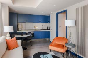 uma sala de estar com armários azuis e uma cadeira laranja em Urban Joy - Holborn By Frankie Says em Londres