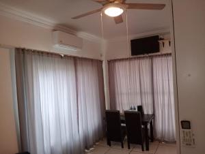 a dining room with white curtains and a table and a ceiling fan at Streetview Suites in Polokwane