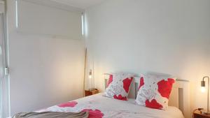 - une chambre avec un lit doté d'oreillers rouges et blancs dans l'établissement Beau T3 à 5 min du Grand Stade avec parking gratuit, à Villeneuve d'Ascq