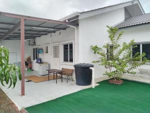 Kapar的住宿－Malay Homestay di Meru, Klang，白色的房子,设有配有桌子的庭院