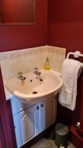 uma casa de banho com um lavatório branco e paredes vermelhas em The Oval by Spires Accommodation a comfortable place to stay in Swadlincote em Church Gresley