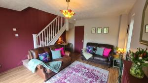 uma sala de estar com duas cadeiras de couro e uma escada em The Oval by Spires Accommodation a comfortable place to stay in Swadlincote em Church Gresley