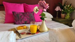 a tray of fruit and a glass of orange juice on a bed at The Oval by Spires Accommodation a comfortable place to stay in Swadlincote in Castle Gresley