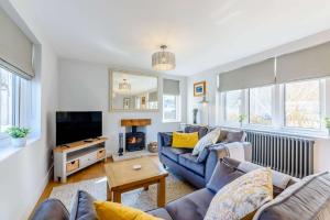 sala de estar con sofá azul y TV en Hillcrest Cottage, en Avening
