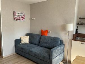 a living room with a blue couch with an orange pillow at Apartement Meerblick in Wunstorf