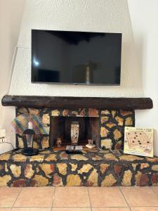 TV de pantalla plana encima de una chimenea de piedra en Rifugio Giudeo, en Balestrate