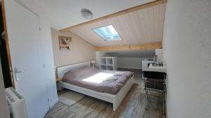 a small bedroom with a bed and a skylight at Aux Lacs et Cascades in Songeson