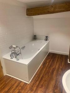 baño con bañera blanca y suelo de madera. en BARN: Sleeps 6, Stansted 12 mins en Hatfield Broad Oak