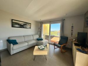 Una sala de estar con un sofá, una mesa y un televisor. en «  Le Sand-Wedge » appartement vue mer, en Wimereux