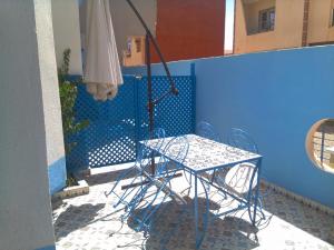 una mesa y una silla en un balcón con sombrilla en Maison d'Hôte à Saïdia, en Saidia 