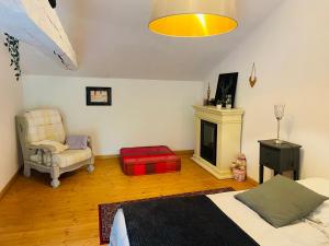 ein Schlafzimmer mit einem Bett, einem Stuhl und einem Kamin in der Unterkunft Suite familiale à la campagne in Sauveterre