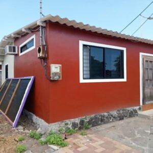 a red house with a door and a window at surf house in Puerto Baquerizo Moreno