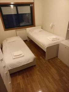 2 camas en una habitación pequeña con ventana en Eixo Atlântico, en Bragança