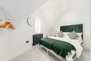 a bedroom with a large bed with a green headboard at The Old Kiosk - Luxe 4 Bed House - Roath Park in Cardiff
