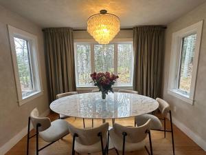 a dining room with a table and chairs and a chandelier at Modern House Family Retreat in Bar Harbor