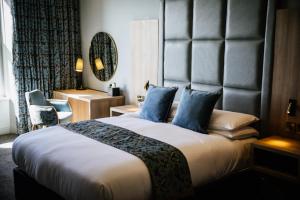a hotel room with a large bed with blue pillows at Clifton Arms Hotel in Lytham St Annes
