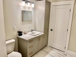 a bathroom with a sink and a toilet and a mirror at Modern Vac Home, private Hot tub, close to airport in Dieppe