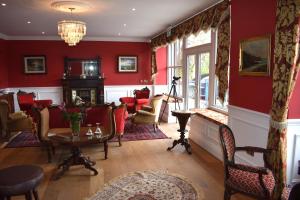un soggiorno con pareti rosse, tavolo e sedie di Tobervilla Guest House a Caherdaniel