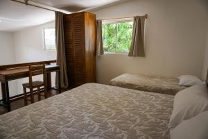 une chambre avec deux lits et un bureau et une fenêtre dans l'établissement Villa SOL, à Santa Teresa