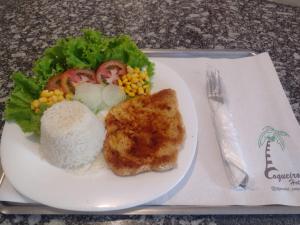 un plato de comida con arroz y verduras en una mesa en Hotel Coqueiros 6, en Carapicuíba