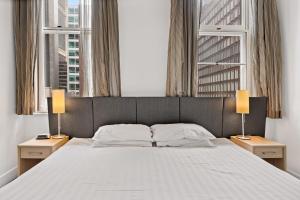 1 dormitorio con 1 cama grande y 2 ventanas en 1-Bed in CBD Perfect for a Melbourne City Break, en Melbourne