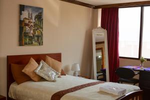1 dormitorio con 1 cama, escritorio y ventanas en Hotel Villa Lafayette, en Quito