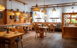 restauracja z drewnianymi stołami, krzesłami i światłami w obiekcie ARKADEN Hotel Kelkheim w mieście Kelkheim