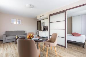 ein Wohnzimmer mit einem Tisch und Stühlen sowie ein Schlafzimmer in der Unterkunft Appart’City Confort Nantes Ouest Saint-Herblain in Saint-Herblain