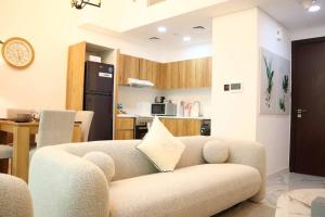 a living room with a couch and a kitchen at Calm Oasis 2BR Apartment Masdar City in Abu Dhabi