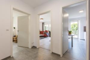 a living room with white walls and a hallway with doors at Birkenstraße 6 Haus II Whg3 in Zingst