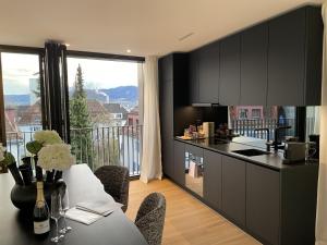 a kitchen with black cabinets and a table with a view at Cosmopolitan Apartments Rosengartenstrasse in Zürich
