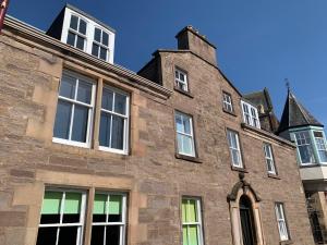 an old brick building with many windows on it at Squirrel Away Apartments in Crieff