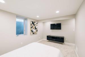 a bedroom with a bed and a tv on the wall at Beautiful luxury home freshly renovated with big yard, seating & grill pad in Cottage Grove