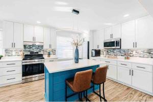 a large kitchen with white cabinets and a blue island at Beautiful luxury home freshly renovated with big yard, seating & grill pad in Cottage Grove
