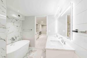 a white bathroom with two sinks and a tub at Beautiful luxury home freshly renovated with big yard, seating & grill pad in Cottage Grove +20 photos