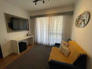 uma sala de estar com um sofá e uma televisão de ecrã plano em The Palace Flat Moema em São Paulo