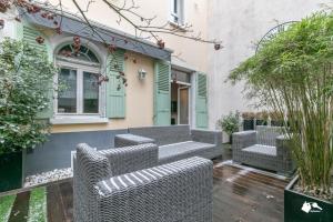 eine Terrasse mit Korbmöbeln vor einem Haus in der Unterkunft MBA - Luxury Berthier Proche des Ternes in Paris