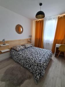 Schlafzimmer mit einem Bett mit einer schwarzen und weißen Bettdecke in der Unterkunft Appartement en centre ville dans résidence calme, RER C 1 min in Brétigny-sur-Orge