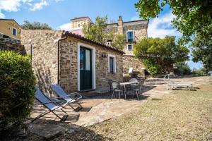 a stone house with chairs and a table in front of it at La Rimessa - ACrapa Mangia in Santa Maria di Castellabate