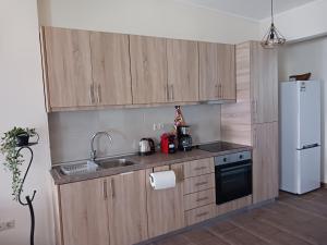 uma cozinha com armários de madeira e um frigorífico branco em Joannas Luxury Apartment em Corfu Town