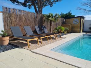 a group of lounge chairs next to a swimming pool at Villa la Ferlandiere in Sainte-Marie-de-Ré